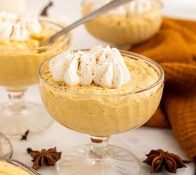 creamy pumpkin mousse easy no bake, A glass dessert dish filled with creamy pumpkin mousse topped with whipped cream and a sprinkle of cinnamon Other mousse dishes and spices are in the background