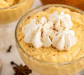 creamy pumpkin mousse easy no bake, A glass dish filled with creamy pumpkin mousse topped with swirls of whipped cream and a sprinkle of cinnamon with star anise and a brown napkin in the background